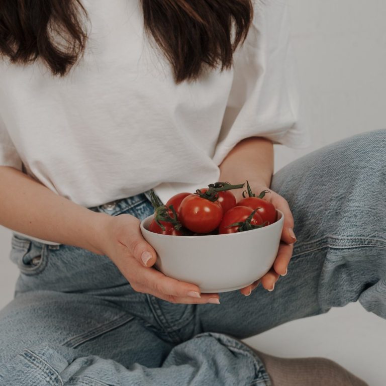 Eine Person hält eine Schüssel mit frischen Tomaten.